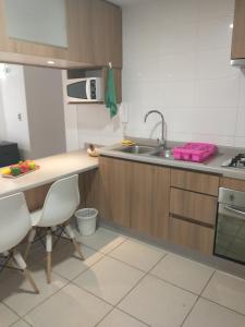 a kitchen with a sink and a counter with chairs at Departamento Alejandra in El Tabo