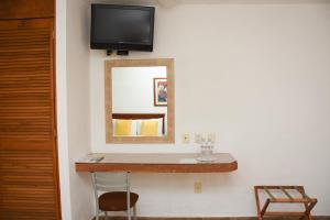 a mirror on a wall with a shelf and a chair at Hotel Camba in Oaxaca City