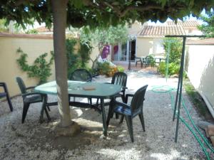 einen Tisch und Stühle unter einem Baum im Hof in der Unterkunft Proche commerces et plage charmant pavillon très bien équipé - AYG10 in Saint Cyprien Plage