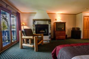 1 dormitorio con 1 cama, chimenea y TV en Wildwood on the Lake en Lake Placid