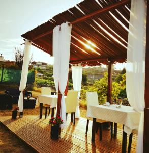 a wooden deck with tables and chairs under a pergola at A Cantaruxa Maruxa Turismo Rural in Mondariz
