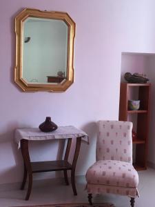 a mirror on a wall next to a chair and a table at B&B La Rampichina in Borgofranco dʼIvrea