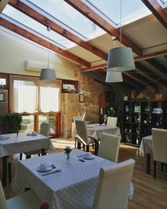 Un restaurante con mesas y sillas blancas y ventanas. en A Cantaruxa Maruxa Turismo Rural, en Mondariz