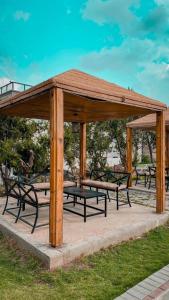 a wooden pavilion with benches and tables in a park at Rawaat Ghaym in Taif