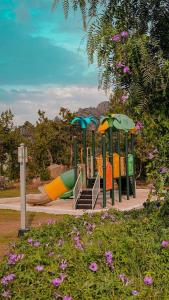 a playground with a slide in a park with flowers at Rawaat Ghaym in Taif