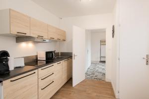 a kitchen with white walls and wooden cabinets at Le stade in Issoire