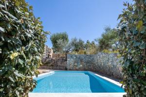 a swimming pool framed by a stone wall at Searocks Villas Exclusive Resort in Kalamata