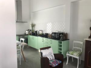 una cocina con armarios verdes, mesa y sillas en Joaninha's Beach House en Glória