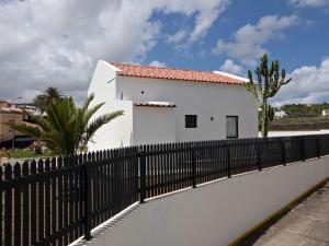 una casa blanca detrás de una valla negra en Joaninha's Beach House, en Glória