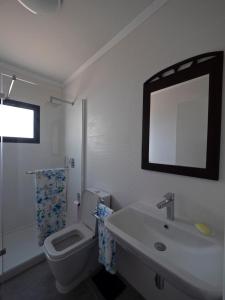 a bathroom with a toilet and a sink and a mirror at Joaninha's Beach House in Glória