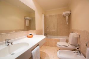 ein Badezimmer mit einem Waschbecken, einem WC und einer Badewanne in der Unterkunft Veneza Hotel in Aveiro