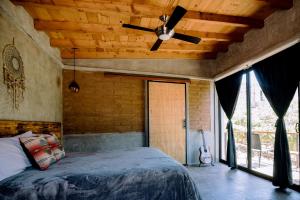 UvaUva eco-retreat في فالي دي جوادالوبي: غرفة نوم مع مروحة سقف وسرير