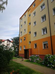 an orange and yellow building with flowers in front of it at Mieszkanie z sercem - dwa pokoje, 300 m od morza in Ustka
