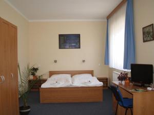 a bedroom with a bed and a desk with a computer at Parkhotel Terezín in Terezín