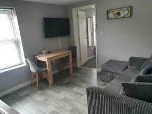 Una sala de estar con una mesa, un sofá y un televisor. en No 3 New Inn Apartments, en Newark-on-Trent