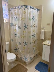 a bathroom with a shower curtain with a toilet and a sink at The Intimate Paradise Close to 876 Beach in Falmouth