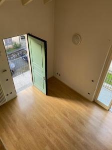 um quarto vazio com uma porta verde e um piso de madeira em Borgo Cairoli em Baveno