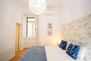 ein Schlafzimmer mit einem großen weißen Bett mit blauen Kissen in der Unterkunft Cosy Baixa Apartment2 in Lissabon