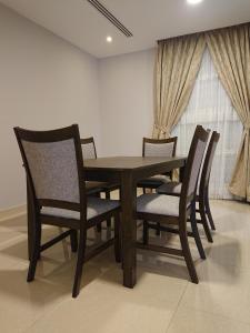 a wooden table and chairs in a room at شقق اجنحة النرجس للشقق المخدومة إقتصادي in Al Khobar