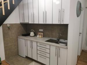 eine Küche mit weißen Schränken und einem Waschbecken in der Unterkunft Apartman Divcigora Sokic in Divčibare