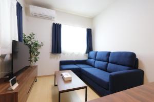 sala de estar con sofá azul y TV en 5 minutes Shin-Osaka 3 en Osaka