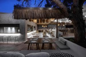 a patio with a table and chairs and a restaurant at Karidi Beach Boutique Suites in Vourvourou