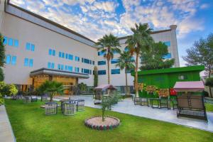 a hotel with tables and chairs and palm trees at The District Hotel Najran in Najran