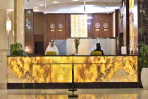 un homme debout derrière un comptoir jaune dans un bâtiment dans l'établissement The District Hotel Najran, à Najran