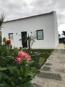 una casa blanca con flores delante en Joaninha's Beach House, en Glória