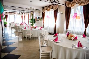 a banquet hall with white tables and chairs with red napkins at Pensiunea Luminita in Târgu Jiu