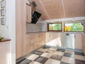 Sønder Nissumにある8 person holiday home in Ulfborgのチェッカー付きの床、木製キャビネット付きのキッチンが備わります。