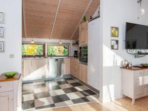 a kitchen with wooden cabinets and a checkered floor at 8 person holiday home in Ulfborg in Sønder Nissum