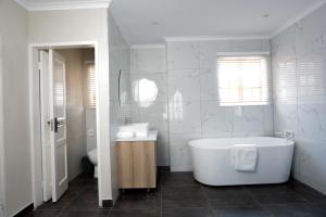 
a bathroom with a tub, sink and toilet at Lefa Boutique Hotel in Rustenburg
