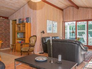ein Wohnzimmer mit einem Ledersofa und einem Tisch in der Unterkunft 6 person holiday home in rsted in Udbyhøj