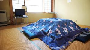 a bed with a blue blanket on the floor at Minpaku Hanaya in Nozawa Onsen