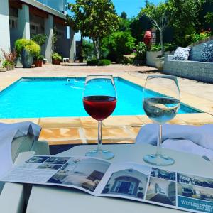 dos copas de vino sentadas en una mesa cerca de una piscina en Waterstone Lodge en Somerset West