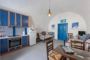 eine Küche und ein Wohnzimmer mit blauen Schränken und einem Tisch in der Unterkunft easy going santorini house in Éxo Goniá