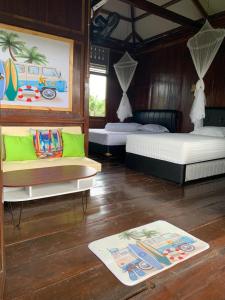 a room with two beds and a couch and a rug at Arya's Surf Camp in Sukabumi