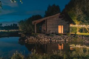 a log cabin by the water at night at Akmeninis Bebras in Zhemoytele