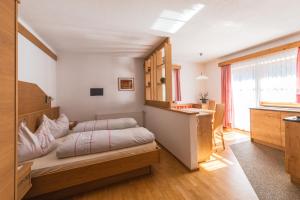 a small bedroom with a bed and a kitchen at Residence Rogger in Dobbiaco