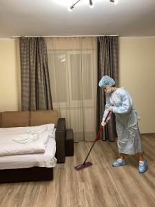 Uma mulher está a limpar um quarto com uma esfregona. em Центр міста! Затишні квартири в новобудові! em Uzhhorod