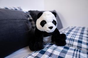 un panda imbottito seduto su un letto di FULL HOUSE Studios - Blue Apartment - WiFi inkl a Magdeburgo