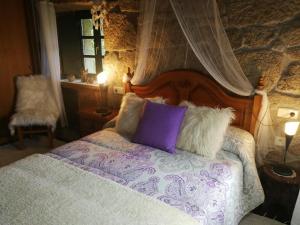 um quarto com uma cama com uma cabeceira e almofadas de madeira em Caserio de Fontes em Nogueira de Ramuin