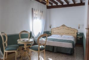 a bedroom with a bed and two chairs and a table at Ca' San Trovaso - 6 Rooms in Venice