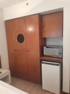a small kitchen with wooden cabinets and a microwave at Condomínio Metropolitan Brasília - Centro de Brasília i15A in Brasilia