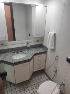 a bathroom with a sink and a mirror and a toilet at Condomínio Metropolitan Brasília - Centro de Brasília i15A in Brasilia