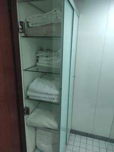 a glass cabinet with folded towels in a bathroom at Condomínio Metropolitan Brasília - Centro de Brasília i15A in Brasilia