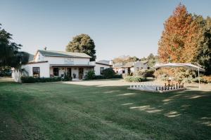 a house with a lawn in front of a building at The Village Lodge in Stormsrivier