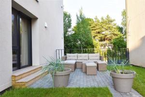 a patio with a couch and two potted plants at Butas trijų kambarių in Palanga +3 photos