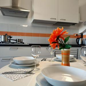 una mesa con platos y vasos y un jarrón con una flor de naranja en Appartamento Velocipede en Cervignano del Friuli